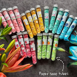 Colorful paper soap sheets in clear tubes with various fruity labels, eco-friendly travel hand soap alternative