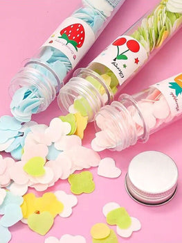 Colorful paper soap sheets spilling out of small transparent bottles on a pink background for portable hand hygiene